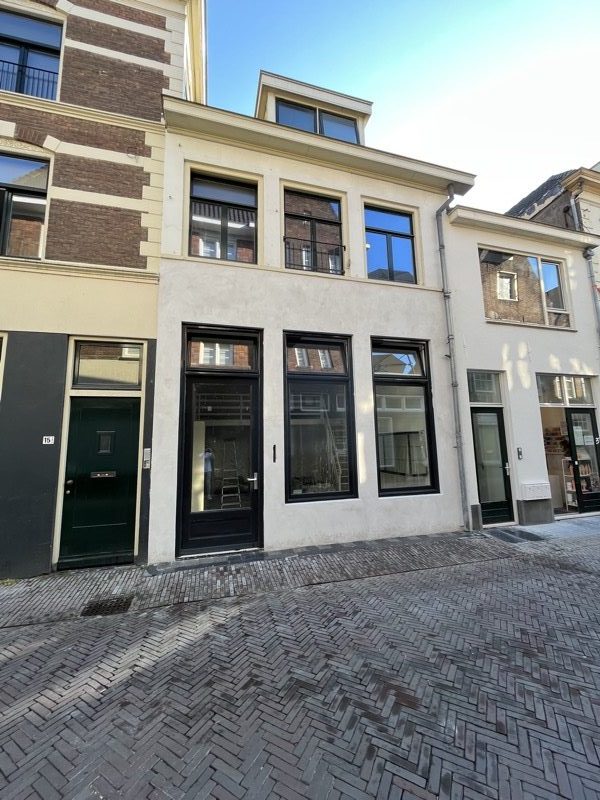 Gepleisterde gevel van een stadspand met zwarte kozijnen